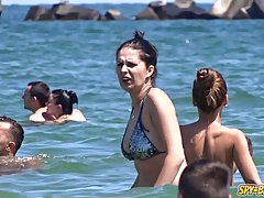 Nude women are sunbathing on the beach, while a horny voyeur is making a hot video